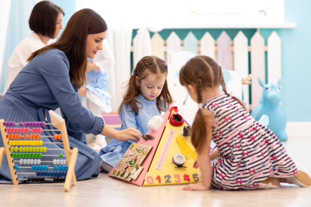 An early years practitioner helping children with a play activity